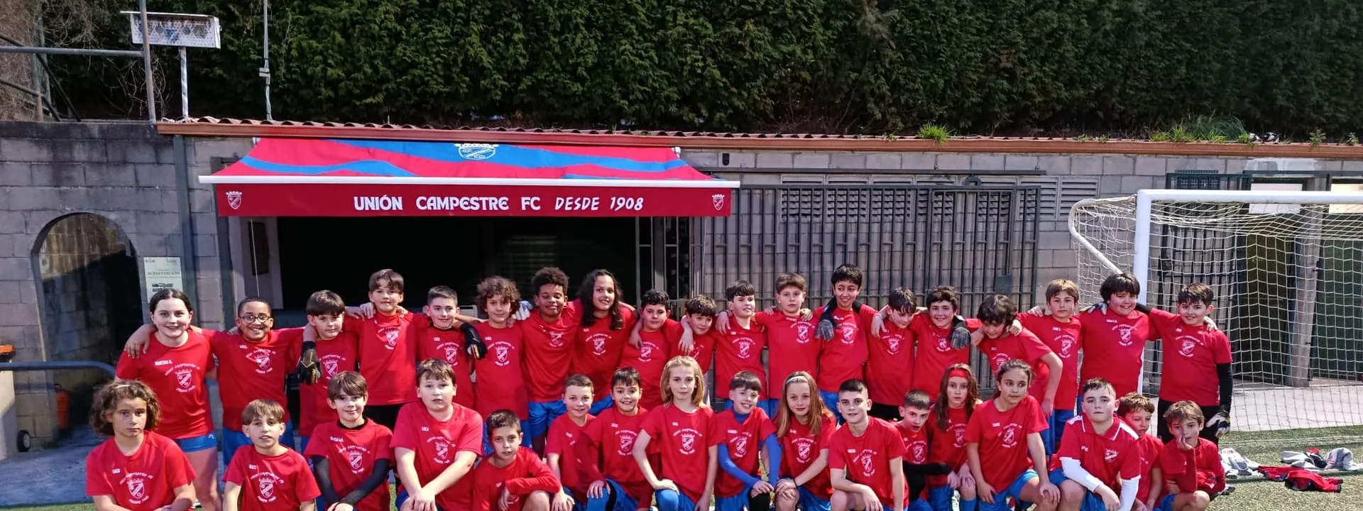 Equipo alevín del Unión Campestre 2026 posando delante del banderín «Unión Campestre FC desde 1908» en el campo de O Redondo